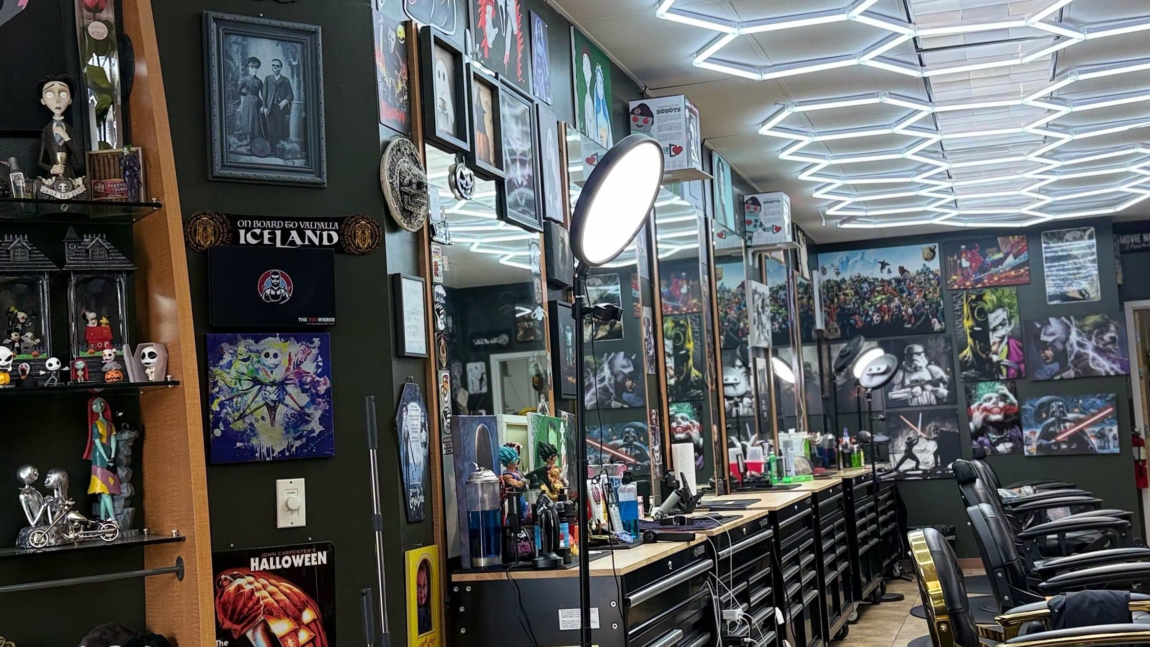 Phantom Fades cutting stations under the hexagon LED ceiling, lined with horror and pop-culture art