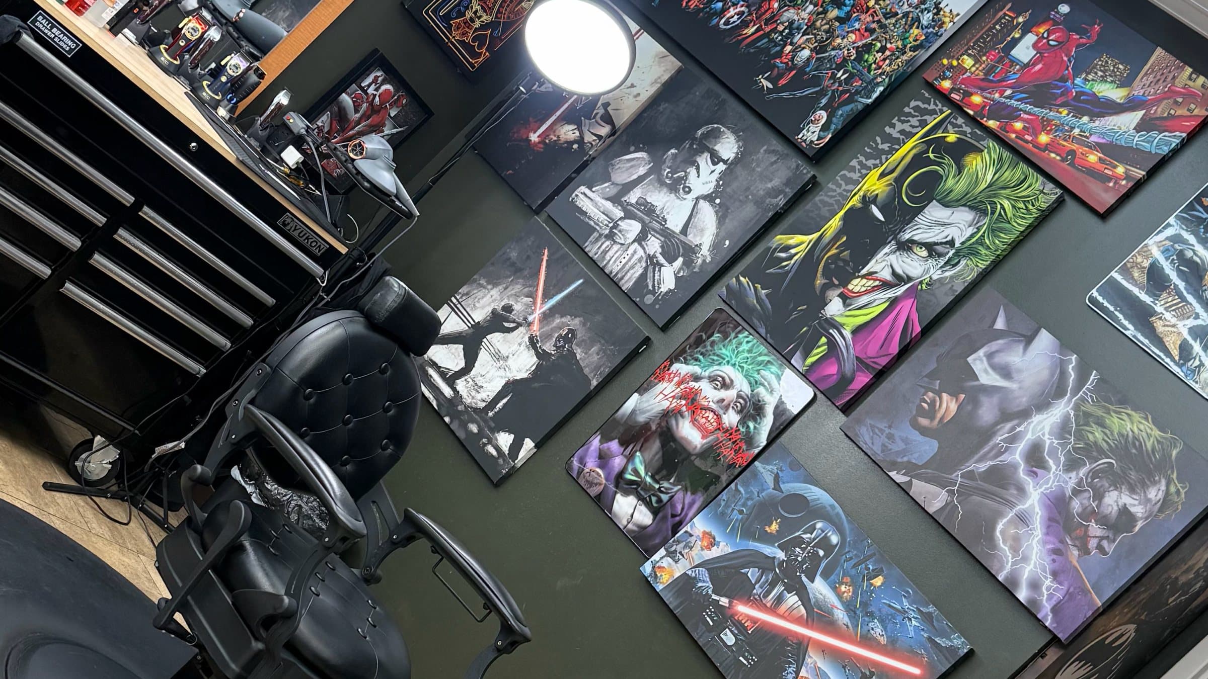 Black tufted barber chair beside a wall of Joker, Batman, and Star Wars canvases at Phantom Fades